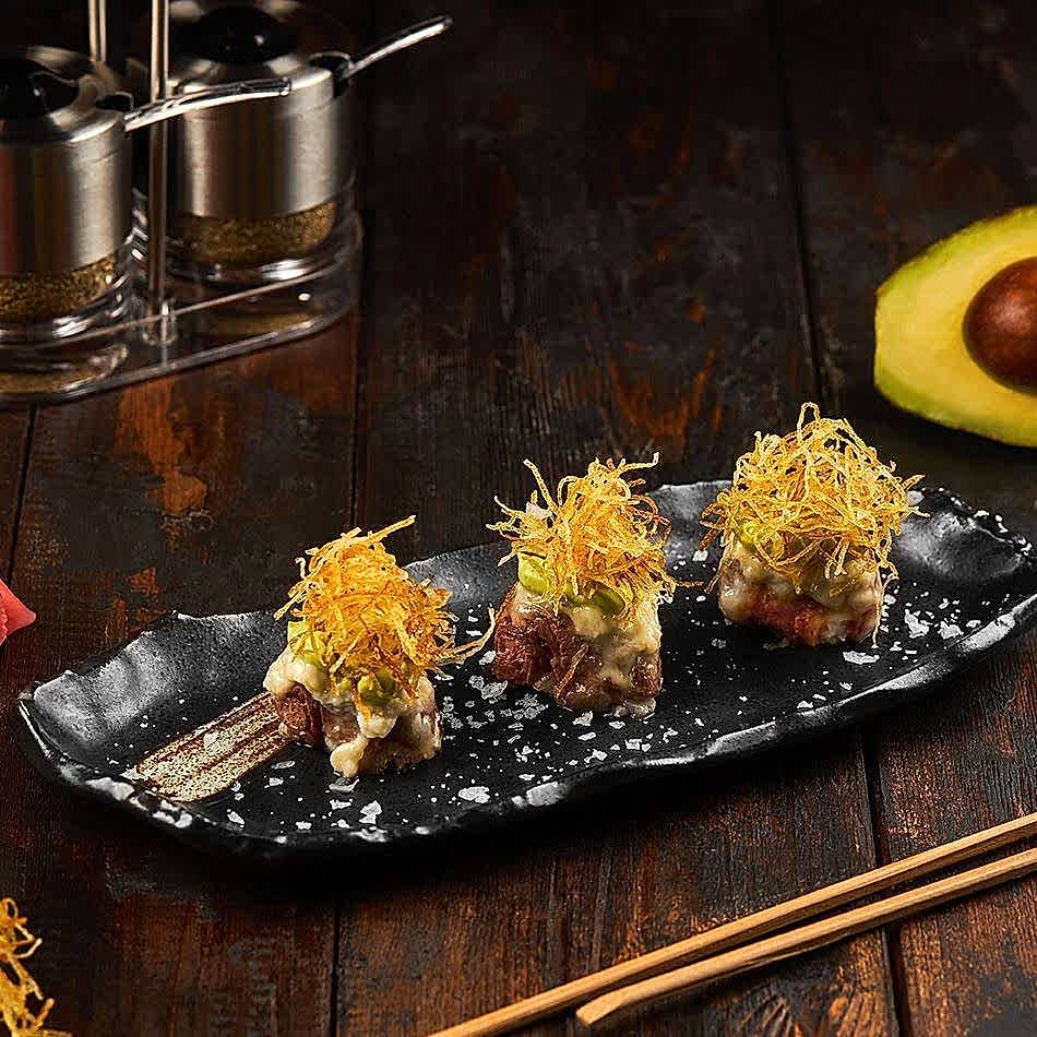 New York Strip meat sushi with layers of avocado cream, crispy potato, and Parmesan on sushi rice.