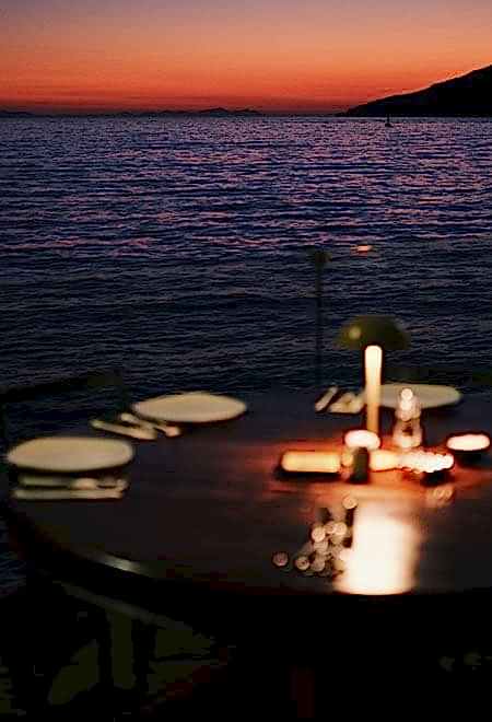 Candle-lit dinner table at Nusr-Et Yalıkavak, with a stunning sunset view over the Aegean Sea, offering an intimate and luxurious dining experience.