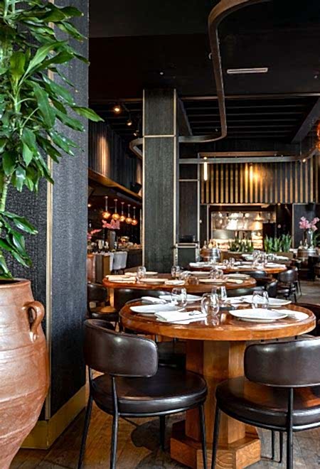 Elegant interior of Nusr-Et Miami with round wooden tables and modern decor, creating a sophisticated steakhouse ambiance.