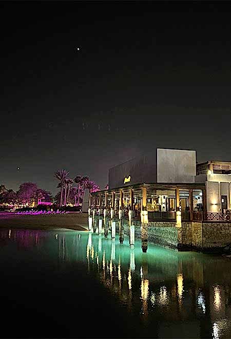 Nusr-Et Doha's stunning waterfront view at night, with the restaurant illuminated against the serene waters of Doha Bay.