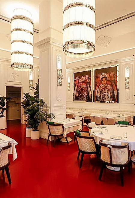 Elegant dining room at Nusr-Et Maçka Palas with white walls, large chandeliers, and red accents, offering a luxurious ambiance.